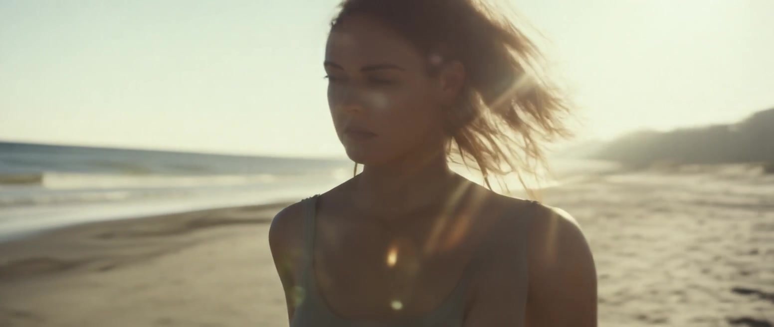 A woman standing on a beach in bright afternoon sunlight